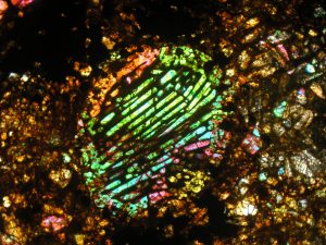 Roštovitá chondrule tvořená olivínem ve výbrusu z kamenného meteoritu